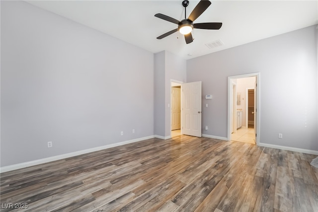 unfurnished bedroom with wood finished floors, baseboards, a ceiling fan, and ensuite bathroom