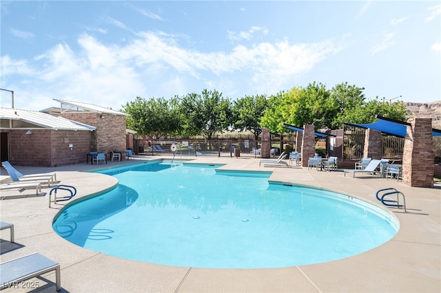 community pool with a patio and fence