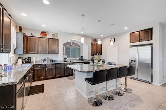 9656 Paraiso Springs St, Las Vegas, NV 89139 - kitchen with stainless steel fridge with ice dispenser, a sink, light stone counters, dark brown cabinets, and recessed lighting