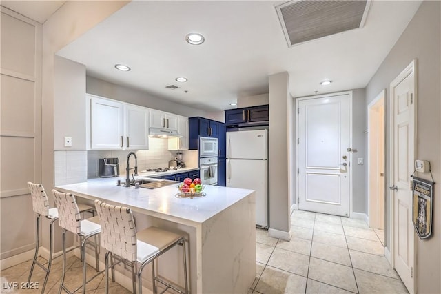 91 E Agate Ave Unit 204, Las Vegas, NV 89123 - kitchen featuring white appliances, blue cabinets, under cabinet range hood, light countertops, and tasteful backsplash