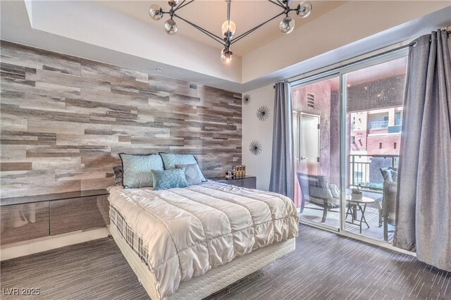 91 E Agate Ave Unit 204, Las Vegas, NV 89123 - bedroom featuring an accent wall, access to exterior, a chandelier, wooden walls, and a raised ceiling