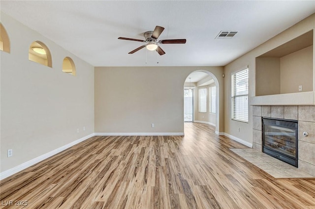 7949 Long Beach St, Las Vegas, NV 89139 - unfurnished living room with light wood-type flooring, a tile fireplace, arched walkways, baseboards, and ceiling fan