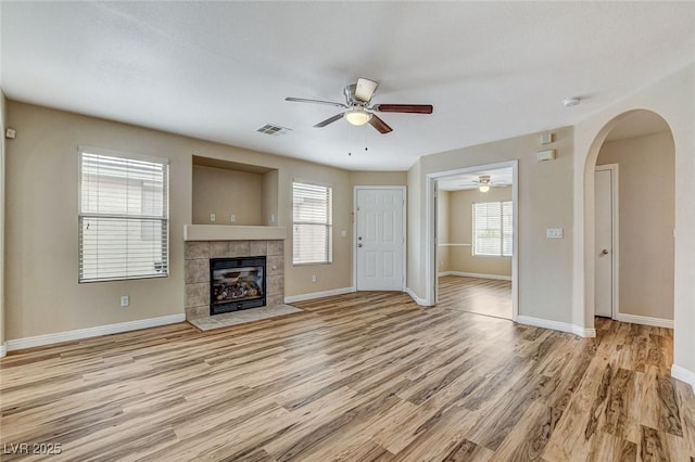 7949 Long Beach St, Las Vegas, NV 89139 - unfurnished living room with a ceiling fan, wood finished floors, baseboards, arched walkways, and a tiled fireplace