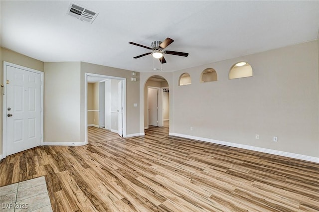 7949 Long Beach St, Las Vegas, NV 89139 - unfurnished living room featuring arched walkways, light wood-style floors, ceiling fan, and baseboards