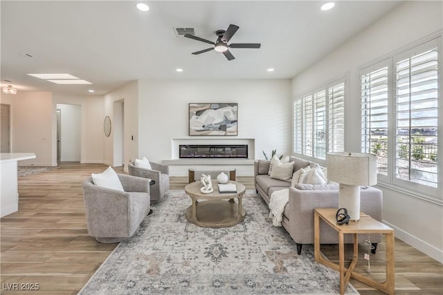 1964 Oliver Springs St, Henderson, NV 89052 - living area with recessed lighting, light wood-style floors, ceiling fan, a glass covered fireplace, and baseboards