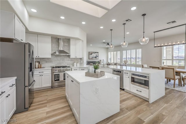 1964 Oliver Springs St, Henderson, NV 89052 - kitchen featuring appliances with stainless steel finishes, wall chimney range hood, a sink, a peninsula, and light wood finished floors