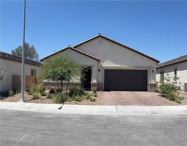 ranch-style house featuring stucco siding, a garage, decorative driveway, a tile roof, and stone siding