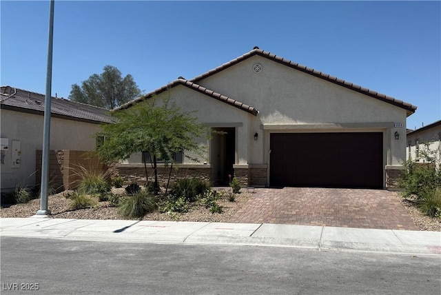 view of front of home with a garage, stucco siding, stone siding, decorative driveway, and a tile roof
