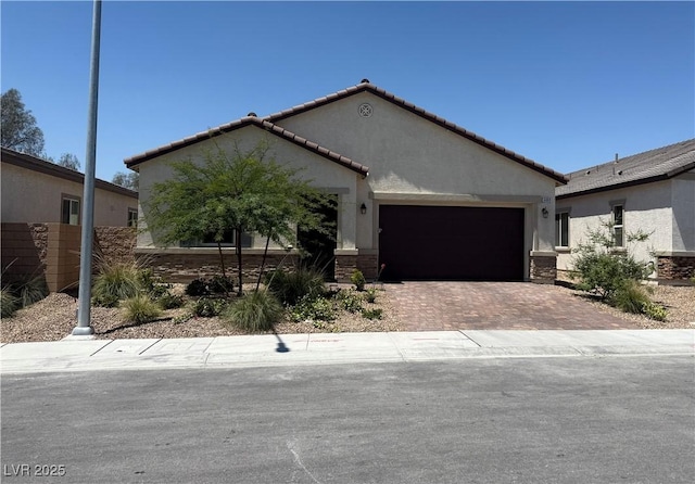 ranch-style home featuring a garage, decorative driveway, stucco siding, and a tile roof