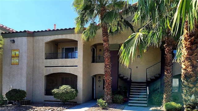 view of front facade with stairs, stucco siding, and a balcony