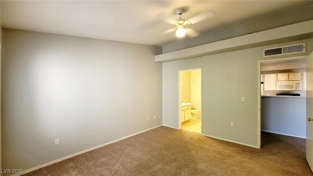 unfurnished bedroom featuring carpet floors, a walk in closet, ensuite bath, baseboards, and a closet