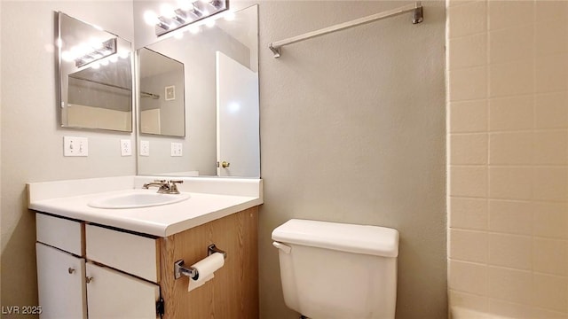 bathroom featuring toilet, vanity, and a shower