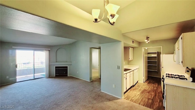 kitchen with light countertops, a fireplace, dishwasher, carpet floors, and baseboards