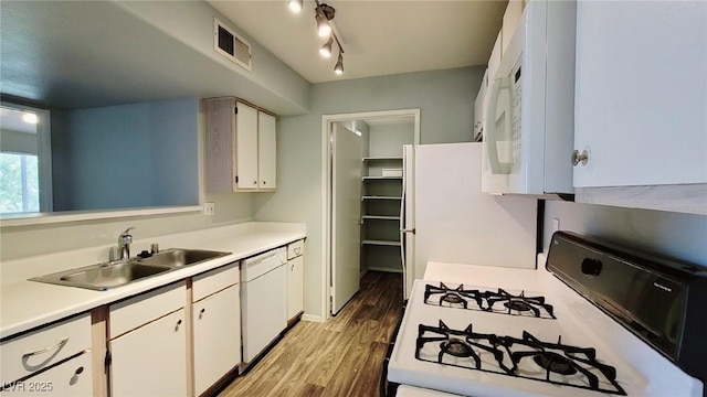 kitchen featuring white appliances, a sink, light countertops, light wood finished floors, and white cabinets