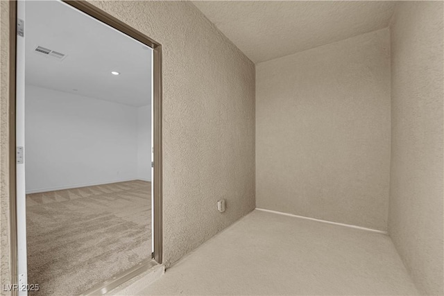 carpeted spare room with a textured wall
