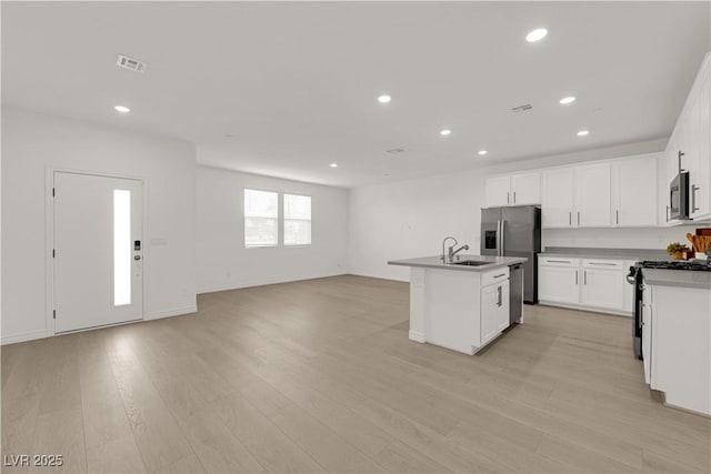 kitchen featuring appliances with stainless steel finishes, open floor plan, recessed lighting, a kitchen island with sink, and light wood-type flooring