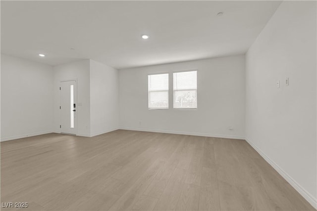 spare room with light wood finished floors, recessed lighting, and baseboards