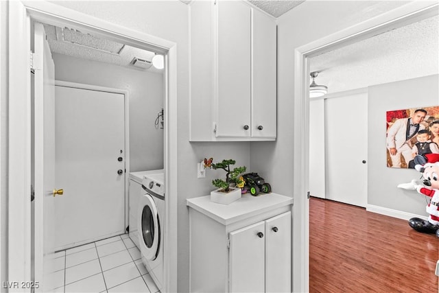washroom with washing machine and clothes dryer, a textured ceiling, and light tile patterned flooring