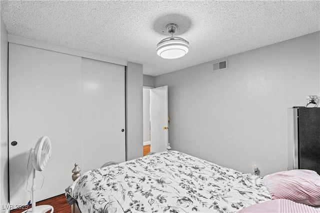 bedroom with a textured ceiling, a closet, and dark wood-style flooring
