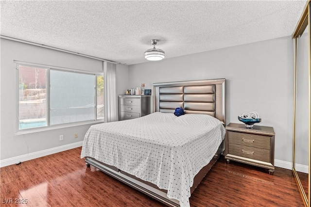 bedroom with dark wood-style floors, baseboards, and a textured ceiling