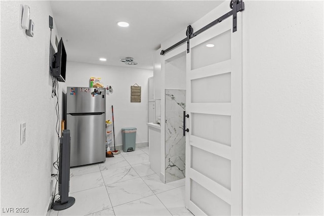 corridor featuring light marble finish floors, a barn door, and recessed lighting