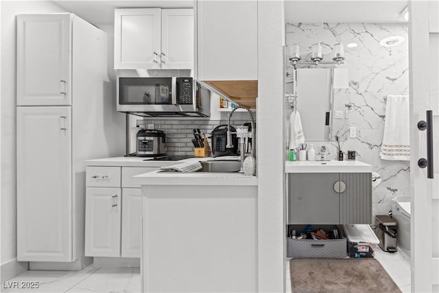 bathroom featuring marble finish flooring, backsplash, and vanity
