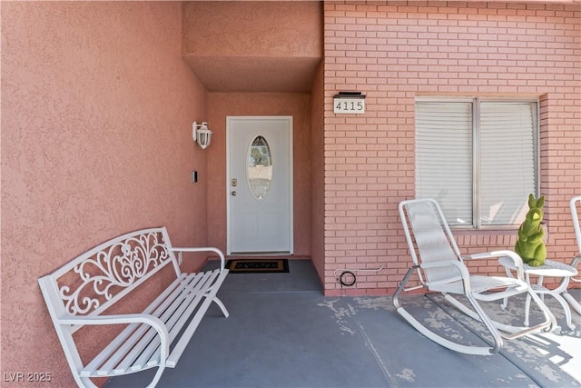 view of exterior entry featuring stucco siding and brick siding