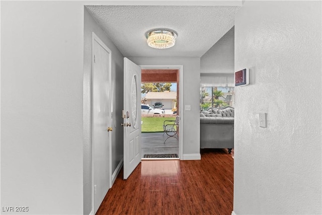 entryway featuring wood finished floors, a textured ceiling, baseboards, and a textured wall