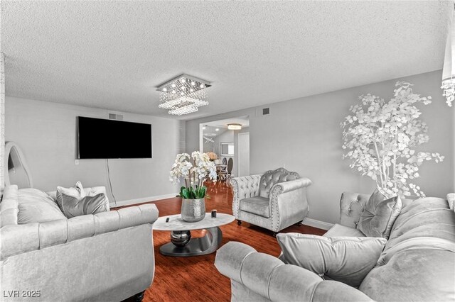 living room featuring wood finished floors, a chandelier, a textured ceiling, and baseboards