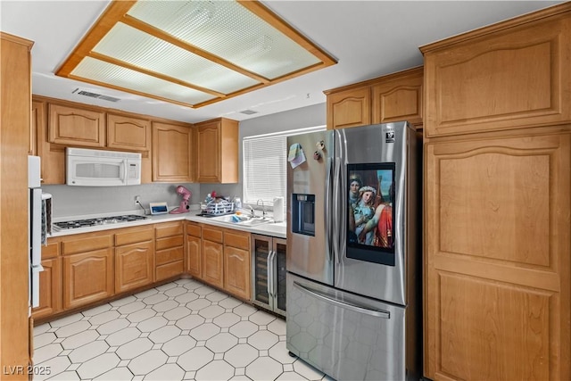 kitchen featuring stainless steel fridge with ice dispenser, white microwave, beverage cooler, light countertops, and light flooring