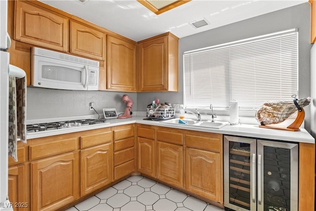 kitchen featuring beverage cooler, white appliances, a sink, and light countertops
