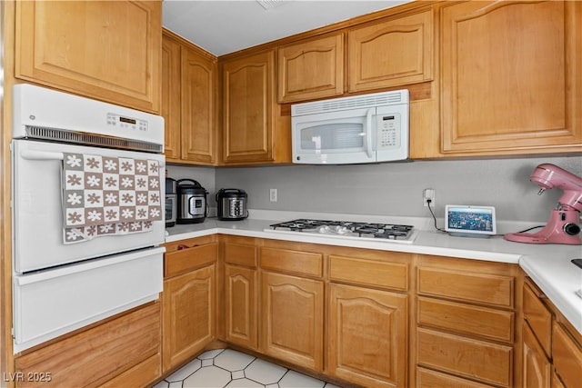 kitchen with white appliances, a warming drawer, and light countertops