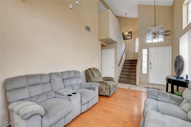 living room with stairs, a high ceiling, and ceiling fan