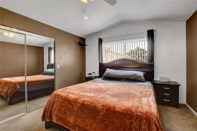bedroom with light carpet, vaulted ceiling, ceiling fan, a closet, and a textured wall