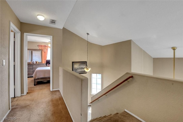 hall with carpet floors, an upstairs landing, healthy amount of natural light, baseboards, and vaulted ceiling