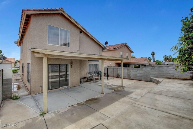 back of property with stucco siding, a fenced backyard, a patio, a tiled roof, and a gate