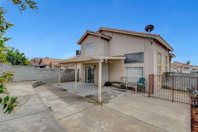 rear view of property featuring stucco siding, a fenced backyard, a patio, a tiled roof, and a ceiling fan