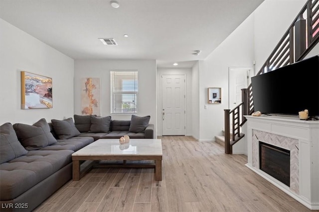 living area with light wood-style flooring, stairway, baseboards, and recessed lighting