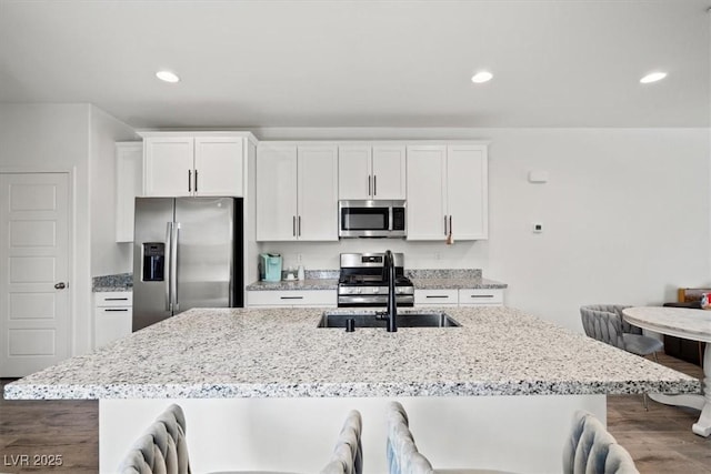 4526 Cloudrest Peak St, North Las Vegas, NV 89031 - kitchen featuring appliances with stainless steel finishes, a sink, white cabinets, a center island with sink, and a breakfast bar area