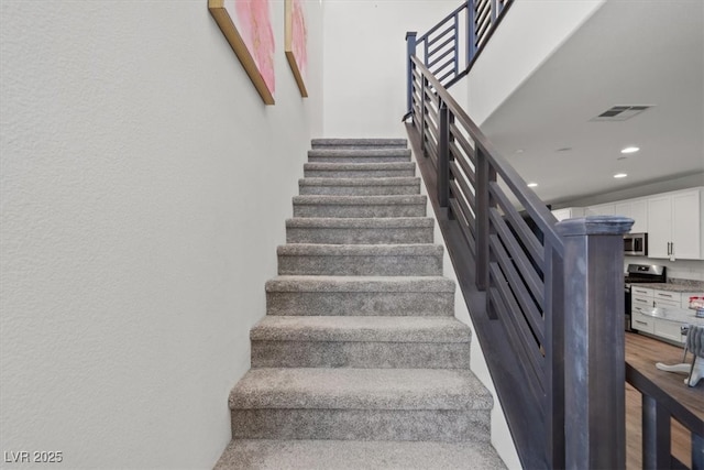 stairway with recessed lighting and wood finished floors