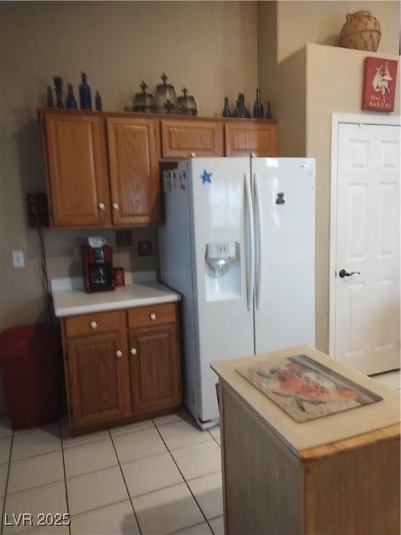 7894 W Patrick Ln, Las Vegas, NV 89113 - kitchen with white refrigerator with ice dispenser, light countertops, brown cabinets, and light tile patterned flooring
