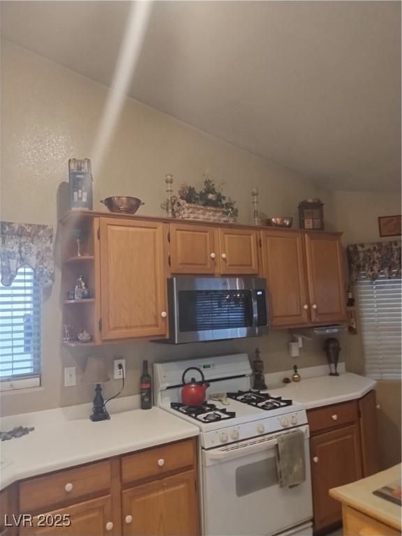 kitchen featuring stainless steel microwave, white gas range oven, vaulted ceiling, light countertops, and open shelves