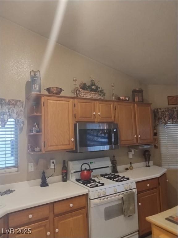7894 W Patrick Ln, Las Vegas, NV 89113 - kitchen with stainless steel microwave, white gas range oven, vaulted ceiling, light countertops, and open shelves