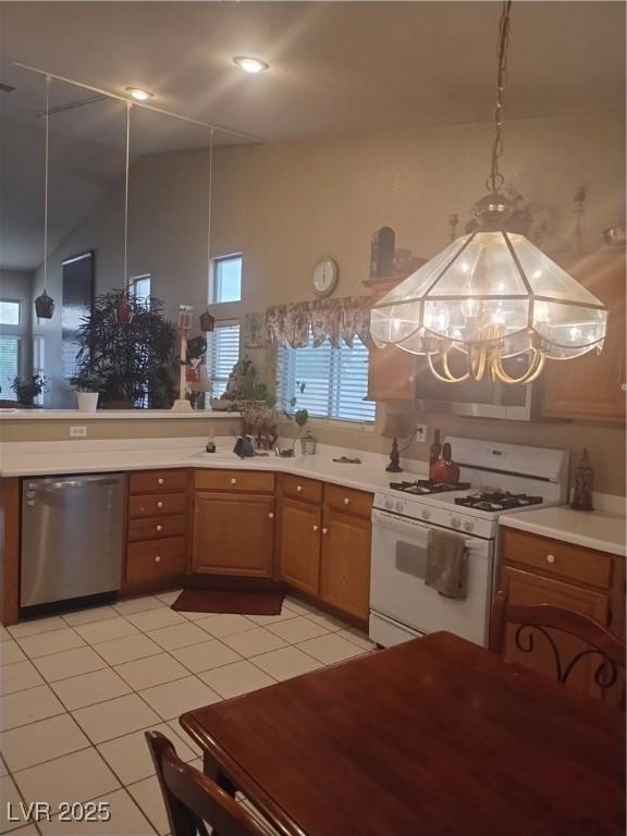 kitchen with white gas stove, stainless steel dishwasher, brown cabinetry, and light countertops