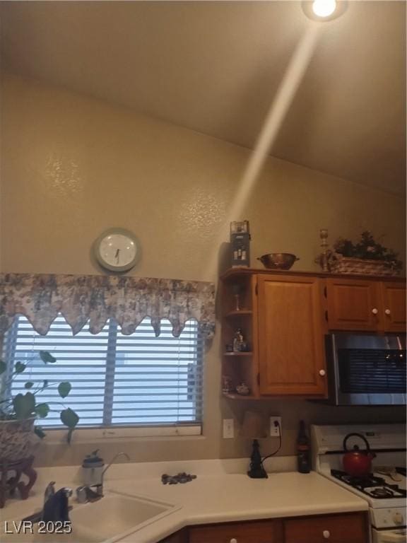 7894 W Patrick Ln, Las Vegas, NV 89113 - kitchen with white range with gas stovetop, stainless steel microwave, a sink, lofted ceiling, and light countertops