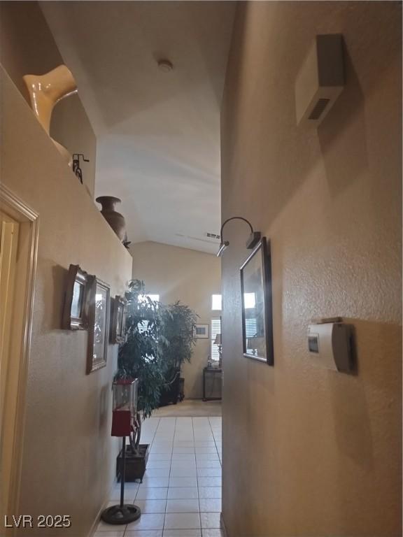 hall with tile patterned floors and vaulted ceiling