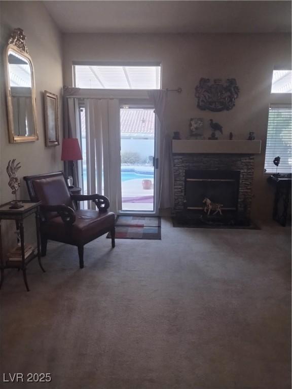 living room featuring a stone fireplace and carpet