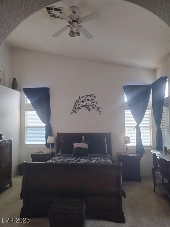 7894 W Patrick Ln, Las Vegas, NV 89113 - bedroom featuring arched walkways, light carpet, and a ceiling fan