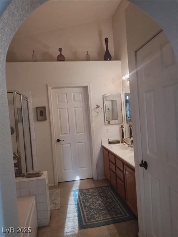 full bath with a shower with door, vanity, and a tub to relax in