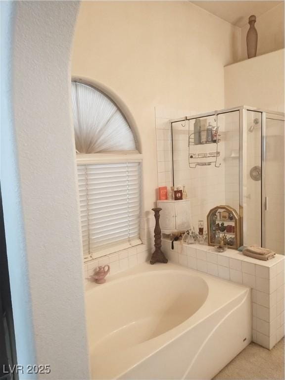 bathroom featuring a shower stall and a bath